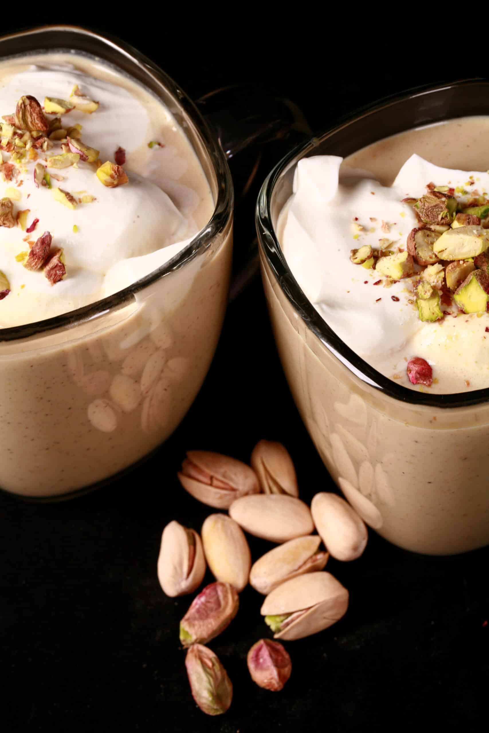 2 mugs of low carb pistachio white hot chocolate topped with whipped cream and chopped pistachios.