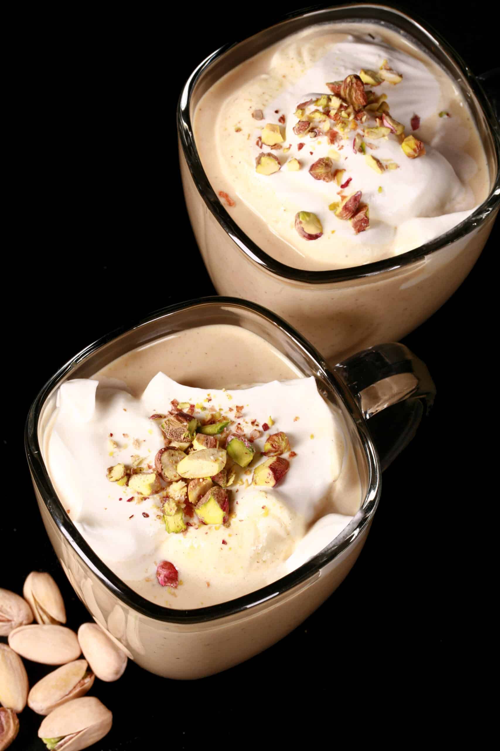 2 mugs of sugar free pistachio white hot chocolate topped with whipped cream and chopped pistachios.