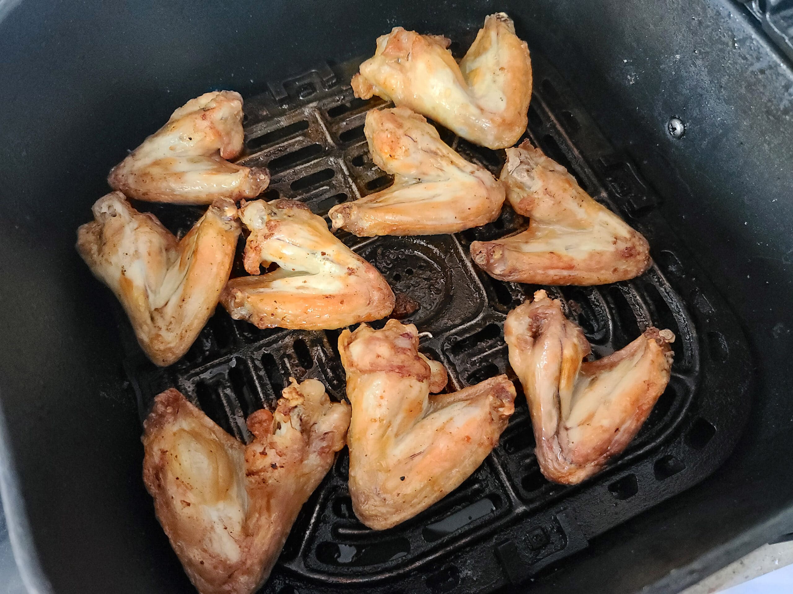 9 chicken wings cooking in an air fryer.