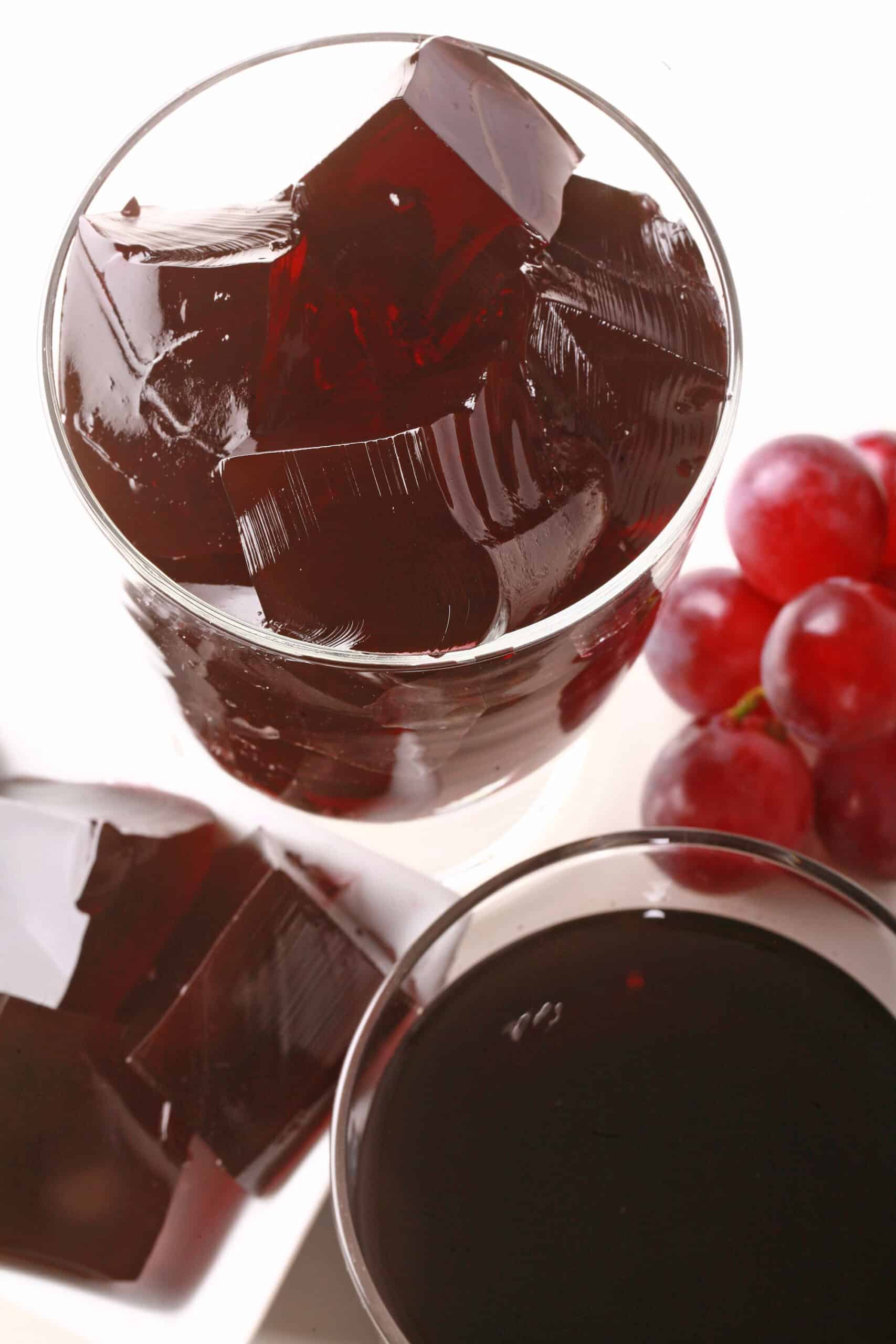 Two glasses of purple homemade sugar free jello, with fresh grapes at the bases.