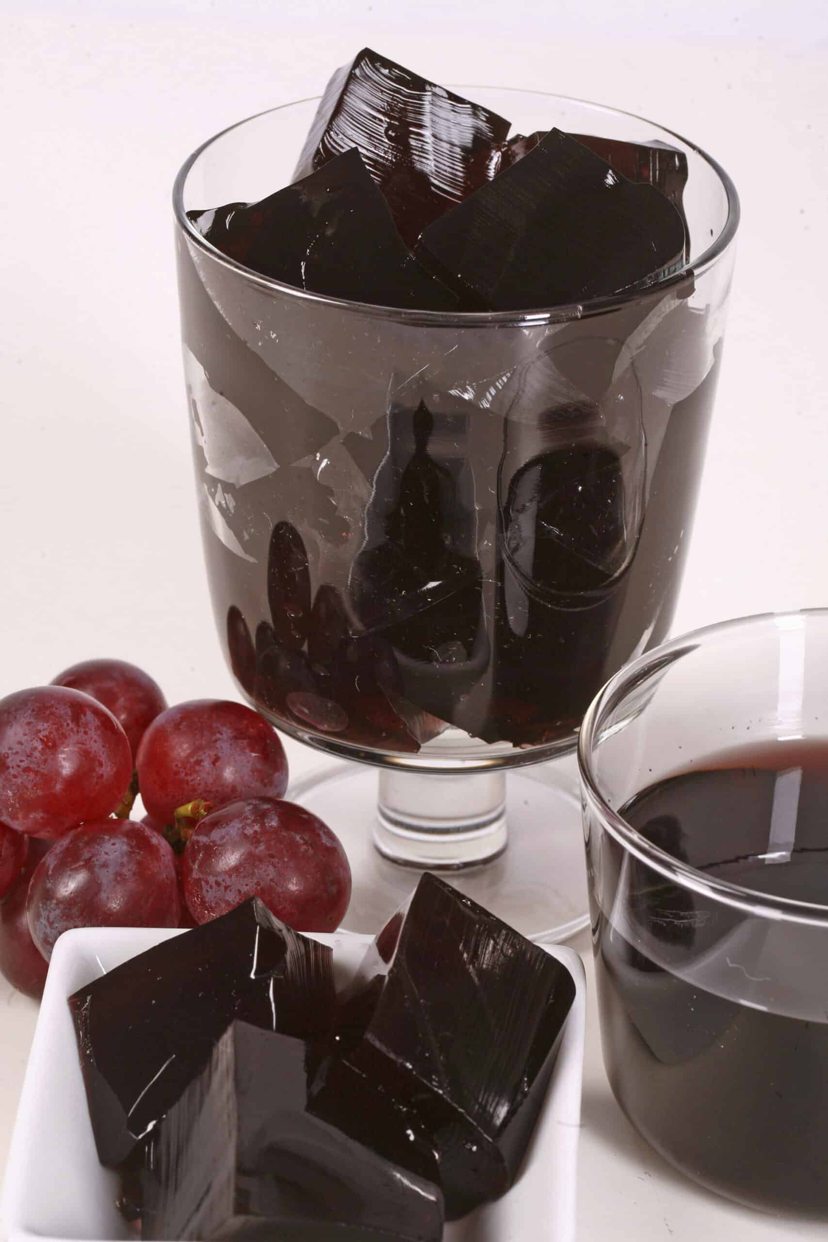 Two glasses of purple homemade sugar free jello, with fresh grapes at the bases.