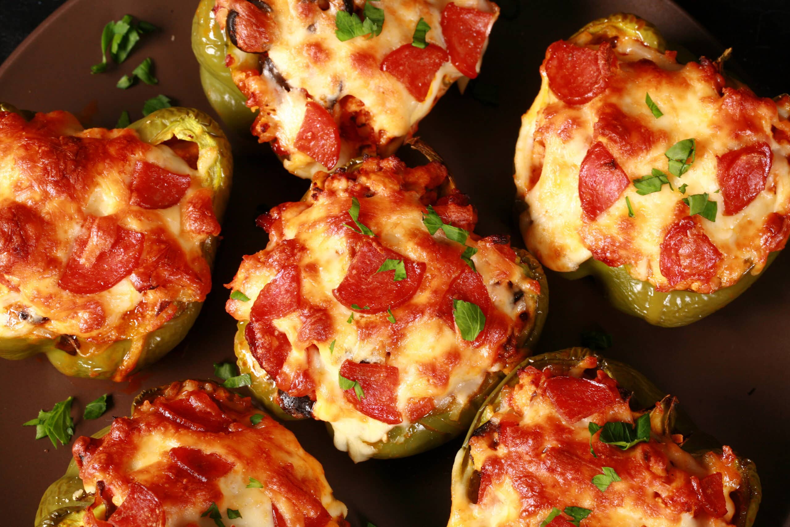 Several keto pizza stuffed peppers on a plate.